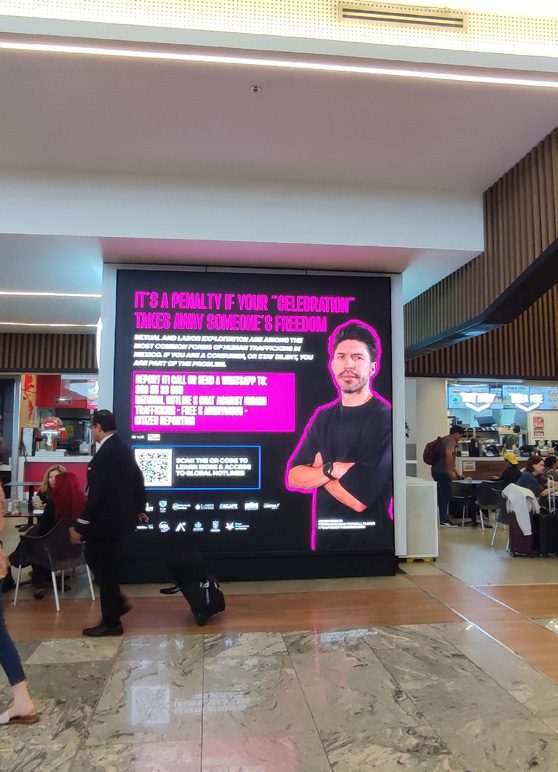 Campaign artwork on a large screen in an airport food court